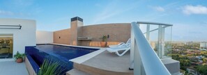 A rooftop pool with a glass balustrade, lounge chairs, and a city view. - Business Apartment with City Views, Pool and Gym (Asunción)