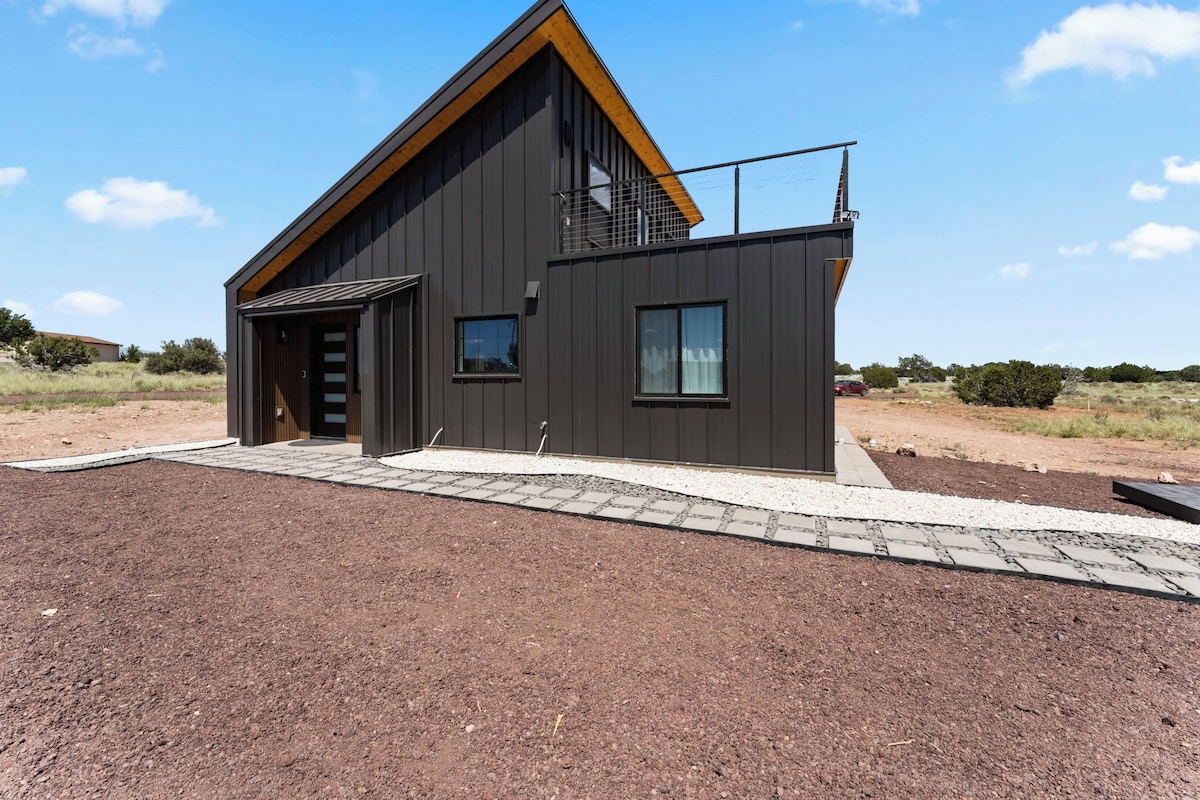 Een modern huis met twee verdiepingen, een schuin dak, een garage en een verharde oprit.