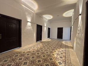 A hallway with patterned flooring, dark doors, and recessed lighting.