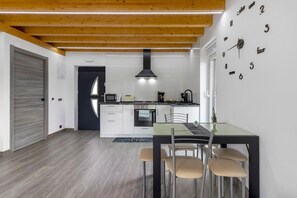 A modern kitchen with white cabinets, a black stove, and a wooden ceiling.
