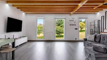 Una sala de estar moderna con un televisor de pantalla plana, un sofá gris y un comedor con mesa y sillas.