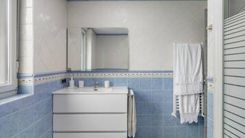 A bathroom with a white sink, a mirror, and a towel hanging on a rack.