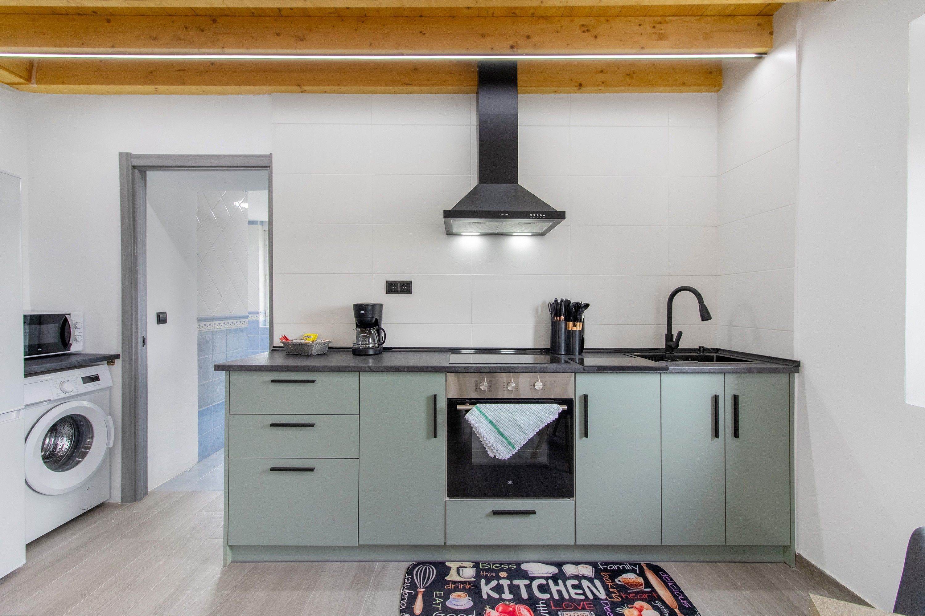 Una cocina compacta con horno integrado, cafetera y lavamanos.