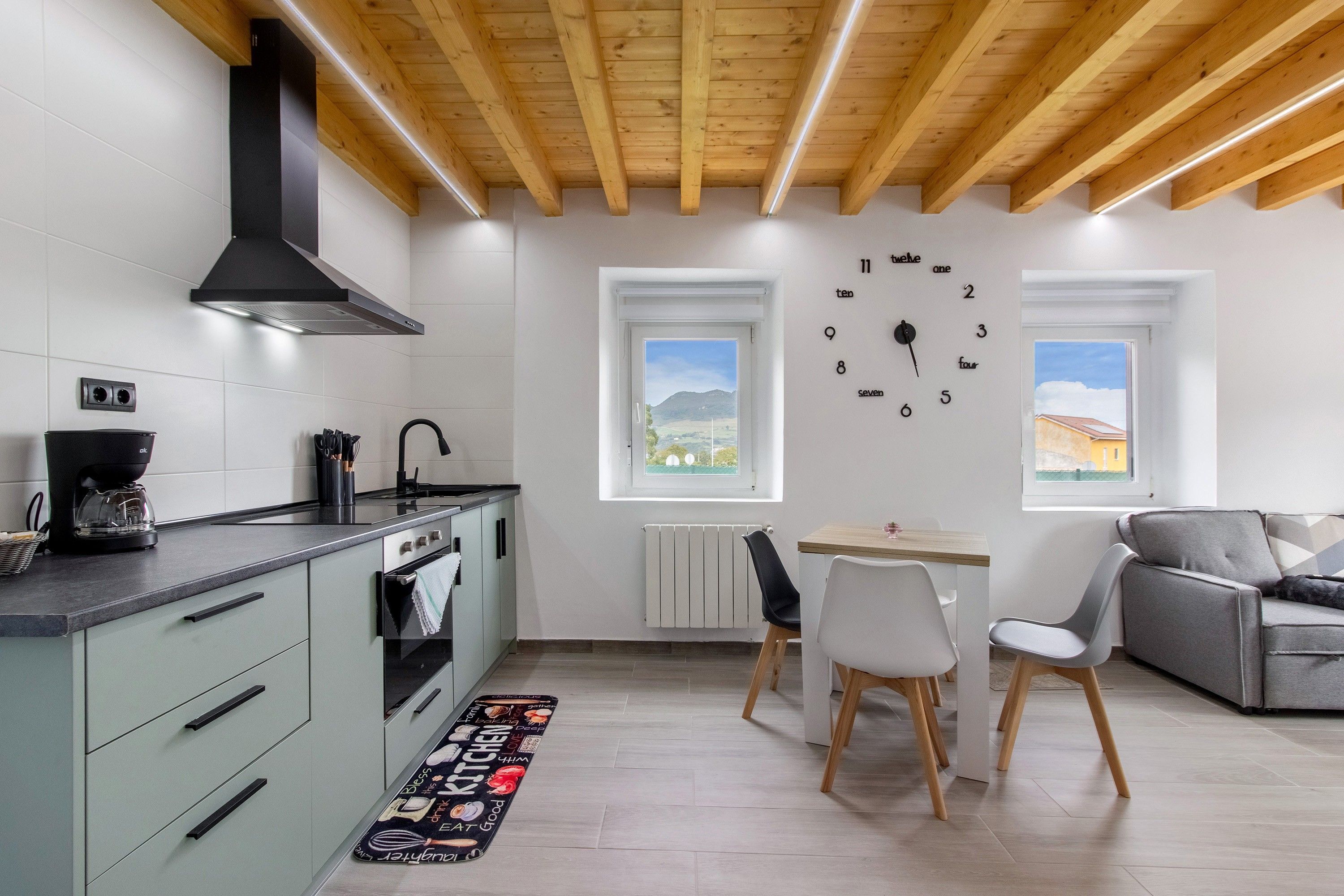 Une cuisine moderne équipée d’un four encastré, d’une machine à café et d’un coin repas avec une table et des chaises.
