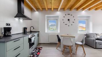 Une cuisine moderne équipée d’un four encastré, d’une machine à café et d’un coin repas avec une table et des chaises.