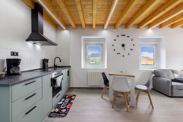 A modern kitchen with a built-in oven, a coffee maker, and a dining area with a table and chairs.
