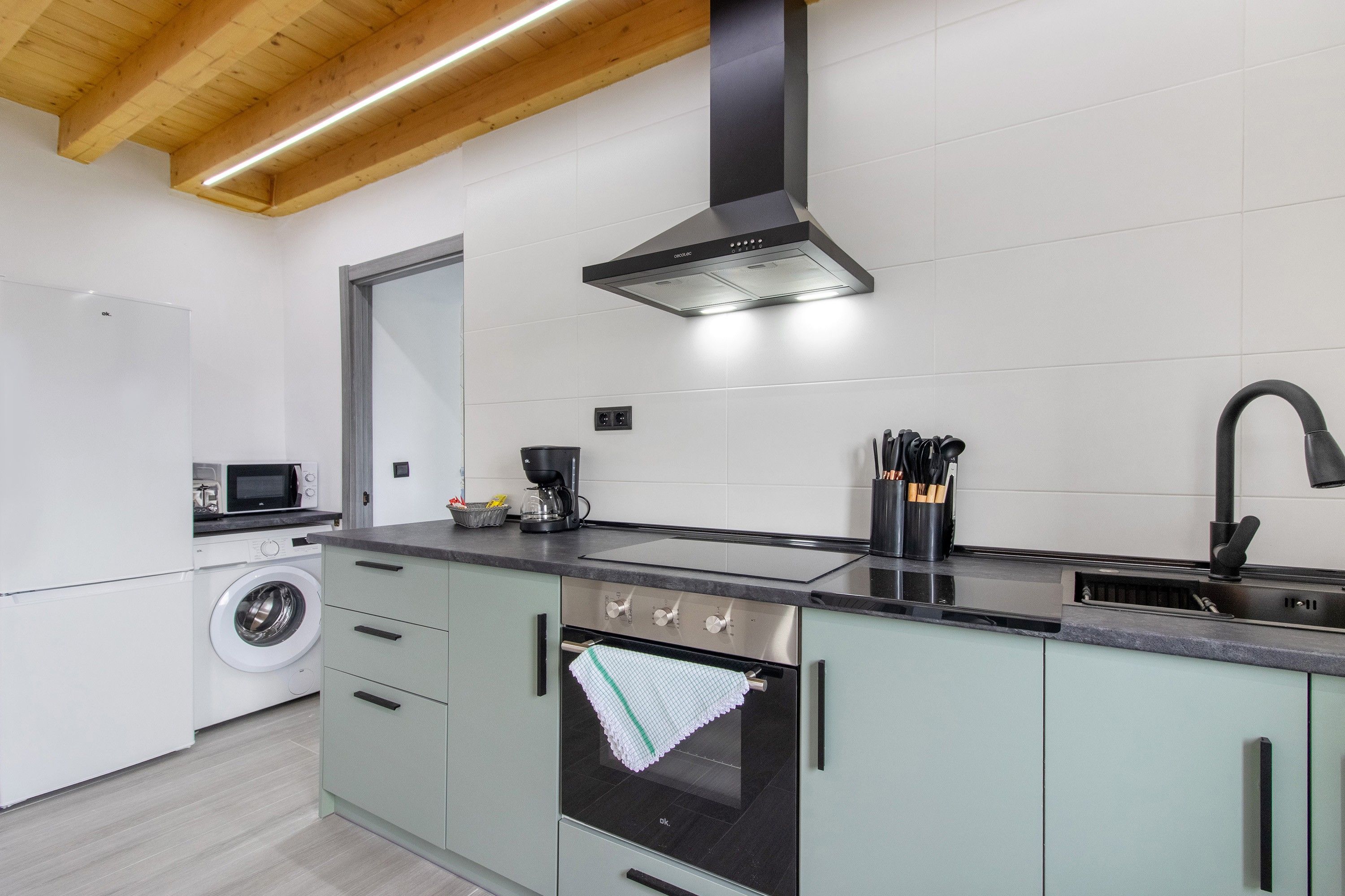 Una cocina moderna con lavadora integrada, cafetera y horno de acero inoxidable.