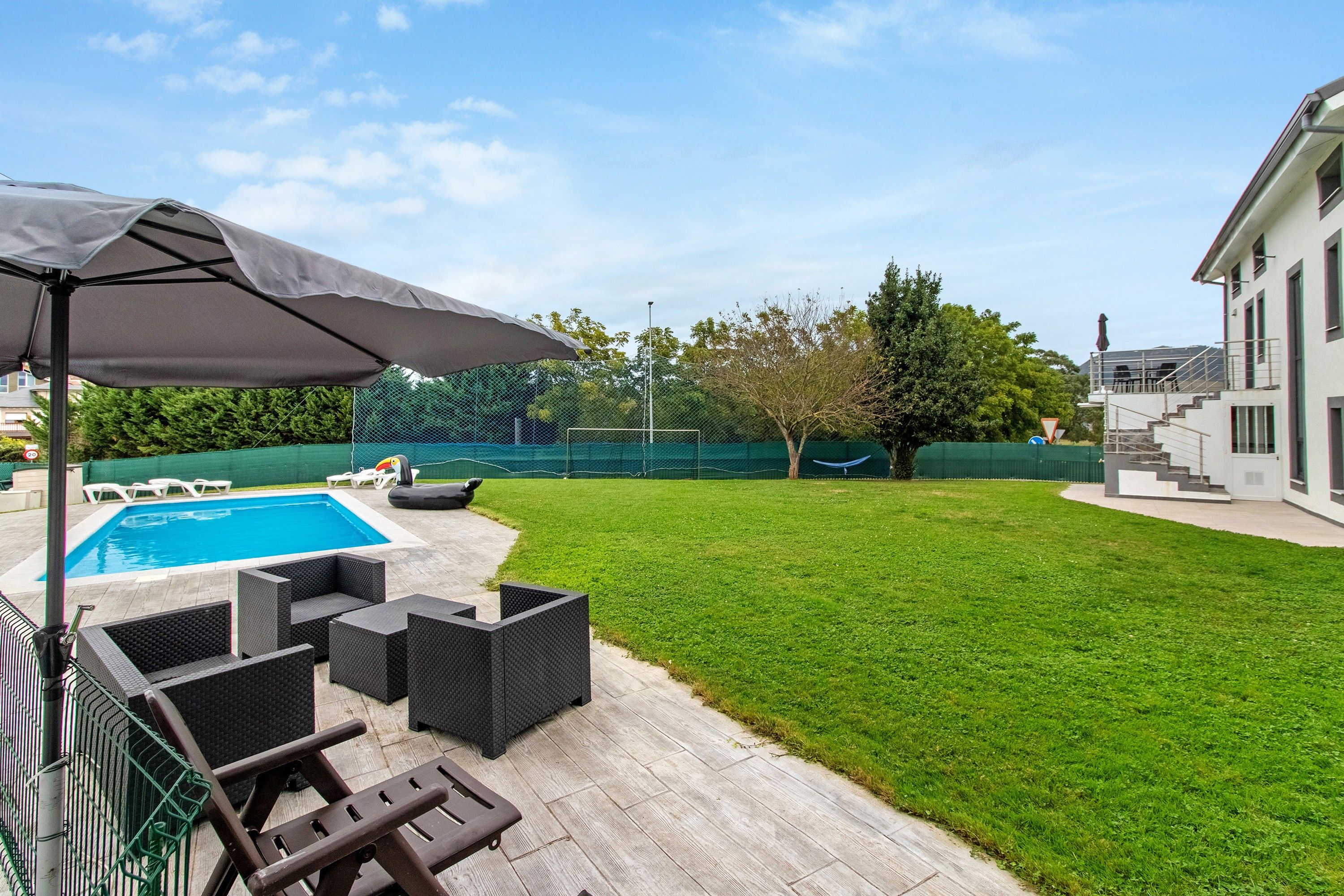 Un jardin avec une piscine, du mobilier d’extérieur et un espace salon abrité.