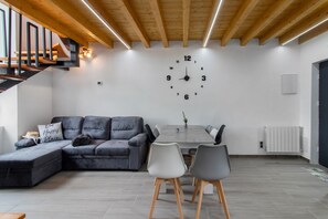 Una sala de estar moderna con un sofá modular, una mesa de comedor con sillas y un reloj de pared grande.