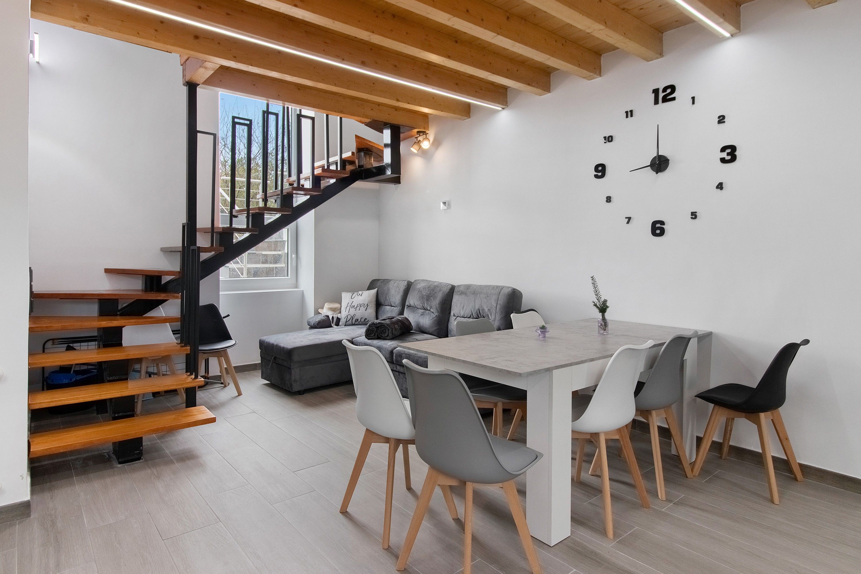 Een modern interieur met een trap, een eethoek en een wandklok.