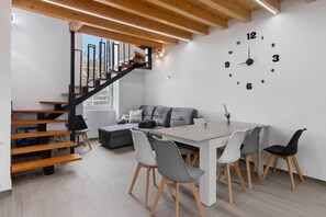 Un interior moderno con una escalera, una zona de comedor y un reloj de pared.