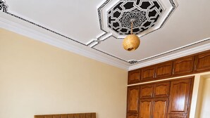 Ein Schlafzimmer mit einem großen Bett, einem Holzschrank und einer verzierten Decke.
