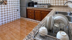 Eine Küche mit einer Granit Arbeitsplatte, Edelstahlgeräten und einem Geschirr-Abtropfgestell.
