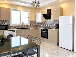 Eine moderne Küche mit Essbereich, ausgestattet mit Geschirrspüler, Mikrowelle, Backofen und einem Samsung-Kühlschrank.