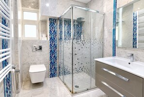 Ein modernes Badezimmer mit Glasdusche, Toilette und Waschtisch mit Spiegel.