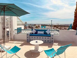 Eine Dachterrasse mit einem blauen Sofa, einem runden Tisch und zwei Stühlen.