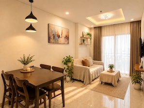 A modern living room with a dining table, sofa, and TV. - Calm 2BR Apt | Big Balcony, Pool & Central (Đà Nẵng)