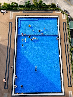 A large rectangular swimming pool with a tiled border, surrounded by a brick walkway. - Calm 2BR Apt | Big Balcony, Pool & Central (Đà Nẵng)