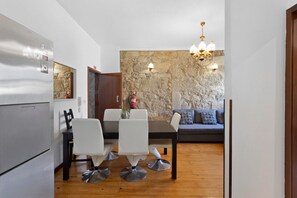 A compact living space with a dining area, a kitchenette, and a stone accent wall. - Apartment 'Fontainhas Stone' with Wi-Fi (Porto)