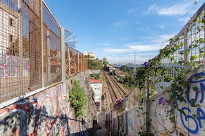 A narrow alley with graffiti on walls, a railway track, and a building with a white facade in the background. - Apartment 'Fontainhas Stone' with Wi-Fi (Porto)