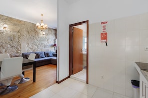 A modern living room with a stone wall, a wooden dining table, and a sofa. - Apartment 'Fontainhas Stone' with Wi-Fi (Porto)