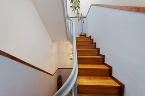 A wooden staircase with a handrail, white walls, and a potted plant at the top. - Apartment 'Fontainhas Stone' with Wi-Fi (Porto)