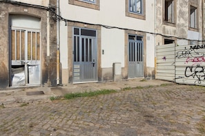A narrow cobblestone street with buildings featuring barred windows and doors, some with visible graffiti. - Apartment 'Fontainhas Stone' with Wi-Fi (Porto)