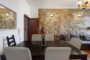 A dining area with a stone wall, a wooden table, and chairs. - Apartment 'Balcony Porto's' with Balcony, Wi-Fi and Air Conditioning (Porto)