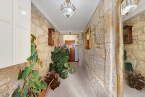 A hallway with stone walls, a wooden door, and a mirror on the right. - Apartment 'Balcony Porto's' with Balcony, Wi-Fi and Air Conditioning (Porto)
