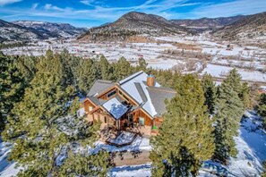 Aerial view of the home nestled among pines overlooking a snowy mountain valley. - Cutbow Lodge | Mountain Views + Hot Tub + Wolf Crk (South Fork)