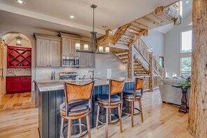 Kitchen island with bar seating next to a custom log staircase. - Cutbow Lodge | Mountain Views + Hot Tub + Wolf Crk (South Fork)