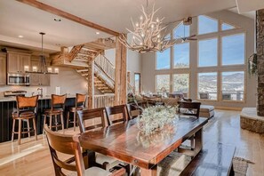 Open dining area with an antler chandelier and views toward the two-story windows. - Cutbow Lodge | Mountain Views + Hot Tub + Wolf Crk (South Fork)
