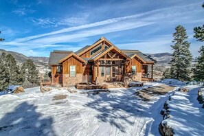 Front exterior of a wood-and-stone cabin home set against snow and mountain peaks. - Cutbow Lodge | Mountain Views + Hot Tub + Wolf Crk (South Fork)