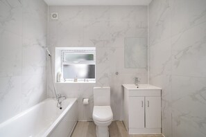 Un baño con bañera, inodoro y lavamanos.