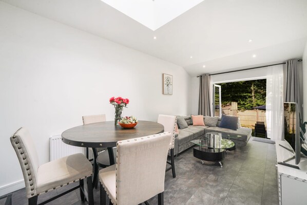 A modern living room with a dining area, a sofa set, and a glass coffee table.