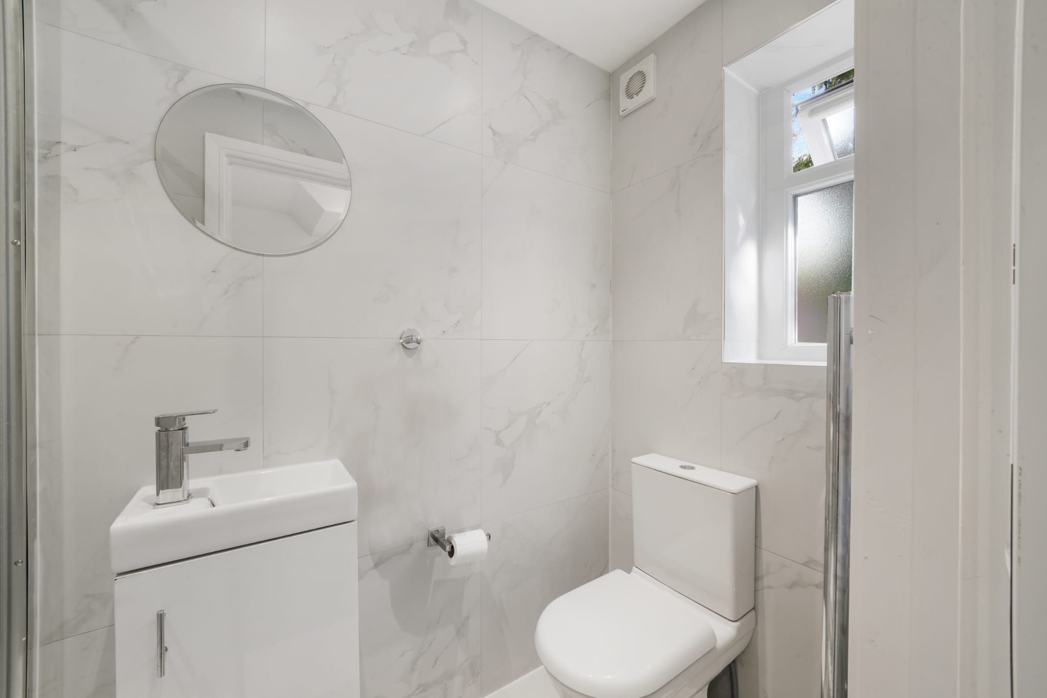 A bathroom with a toilet, sink, and mirror.