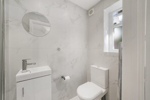 Een badkamer met toilet, wastafel en spiegel.