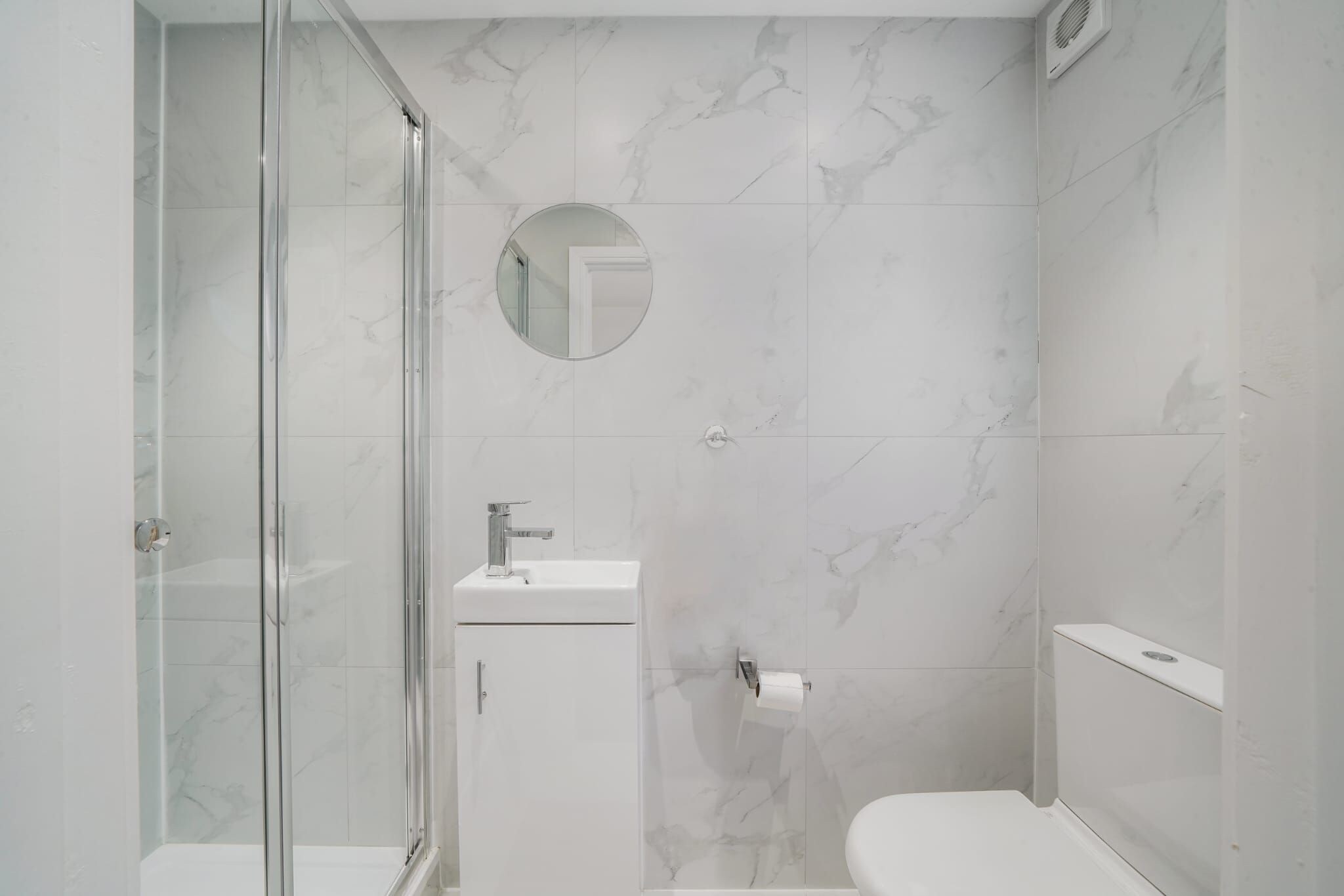 A modern bathroom with a glass-enclosed shower, a sink with a mirror, and a toilet.