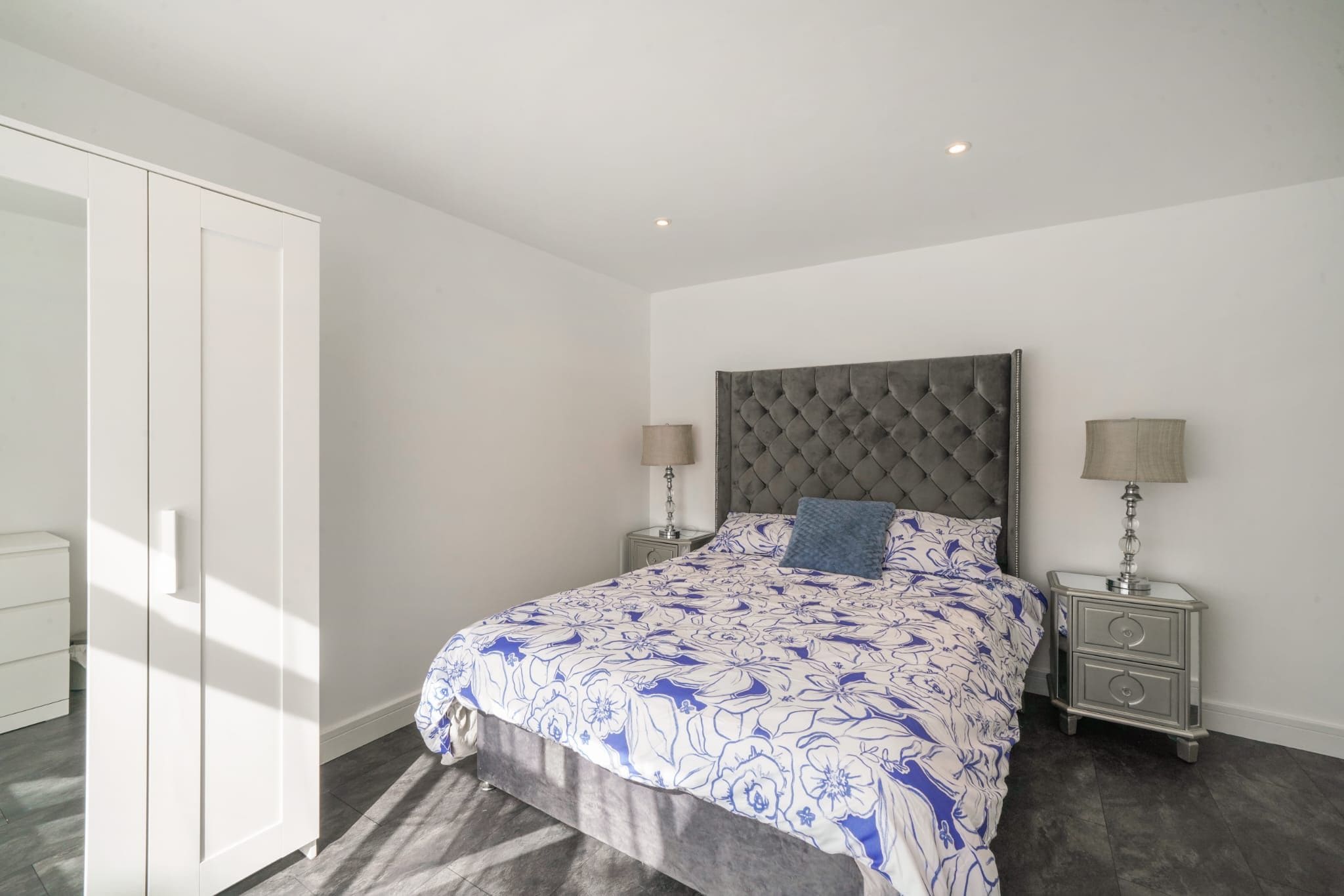 A bedroom with a bed, two bedside tables, a wardrobe, and a ceiling light.