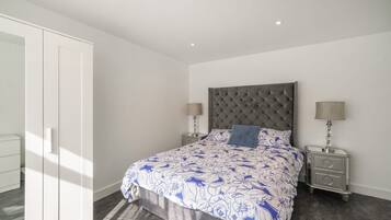 A bedroom with a bed, two bedside tables, a wardrobe, and a ceiling light.