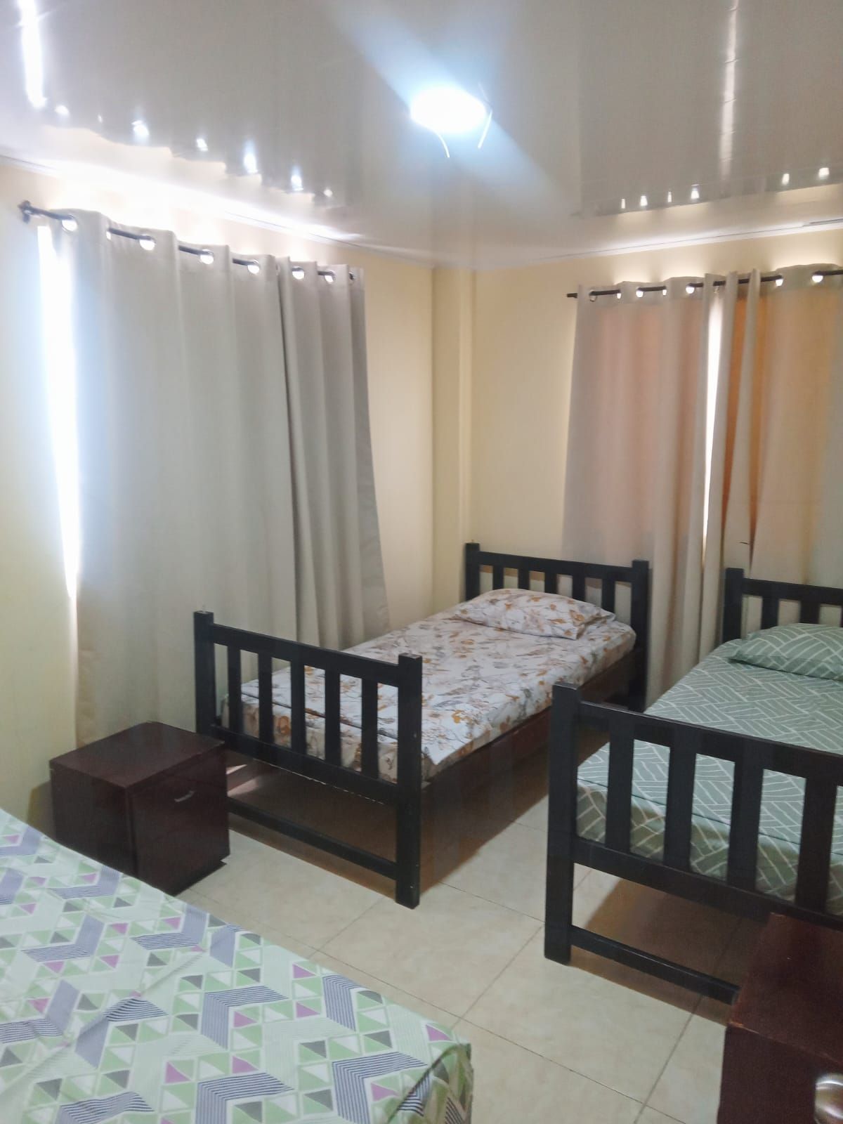 Una habitación con dos camas individuales, una mesita y una cortina.