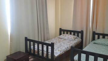 Una habitación con dos camas individuales, una mesita y una cortina.