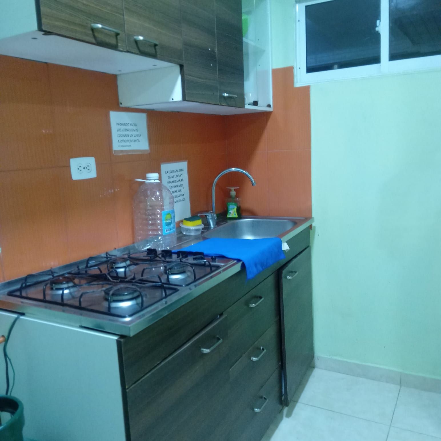 Eine kleine Küche mit Gaskochfeld, Spüle und Schränken.