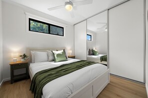 A bedroom with a bed, bedside tables, a nightstand, a window, and a ceiling fan. - Onkaparinga Hideaway Beach Days and Reef Adventures (Port Noarlunga)