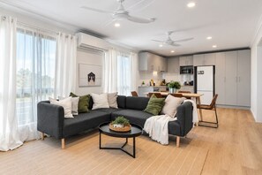 A modern living room with a sectional sofa, a round coffee table, and a dining area with a table and chairs.