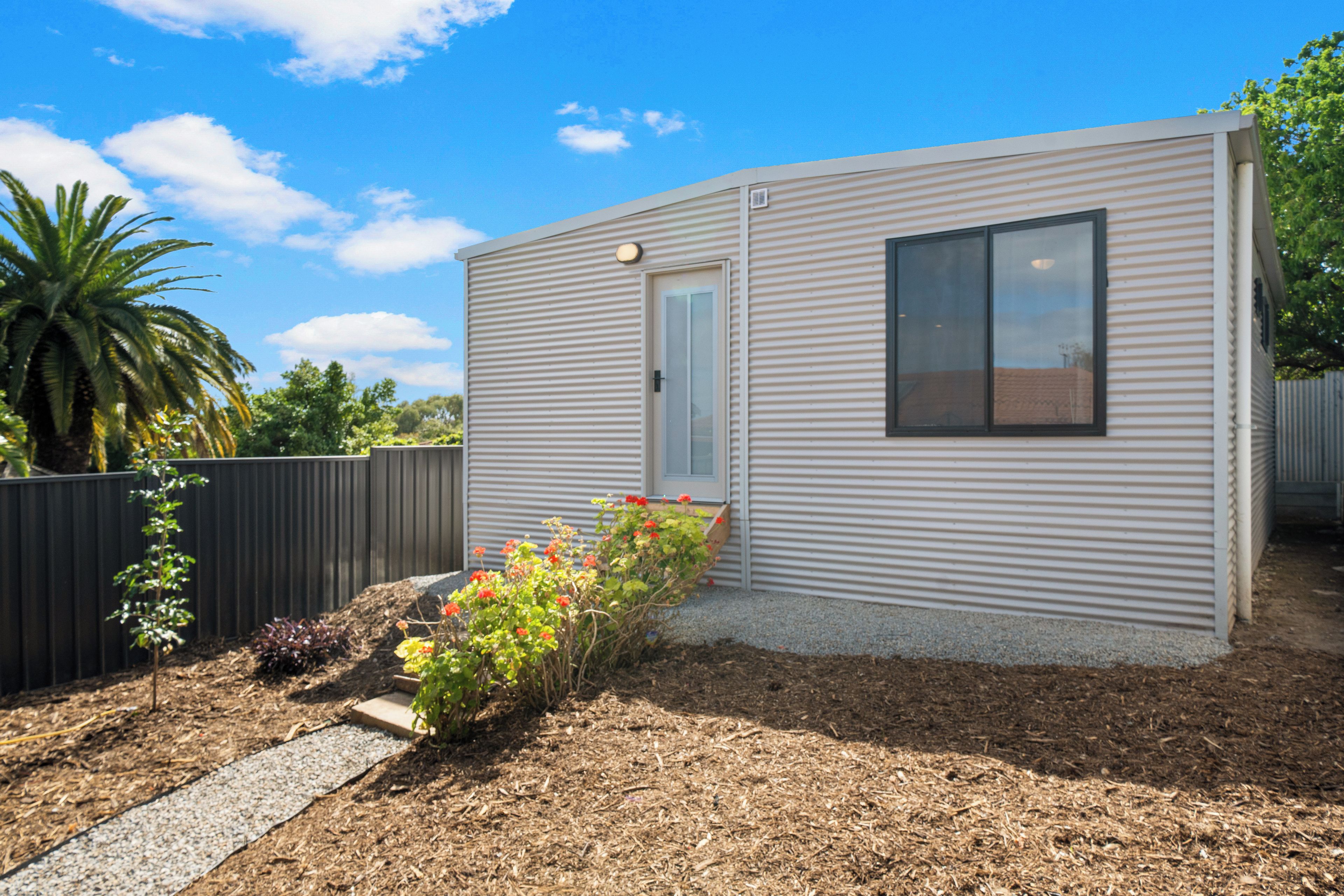 A modern single-story building with a flat roof, a door, and a window.