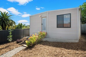 A modern single-story building with a flat roof, a door, and a window.