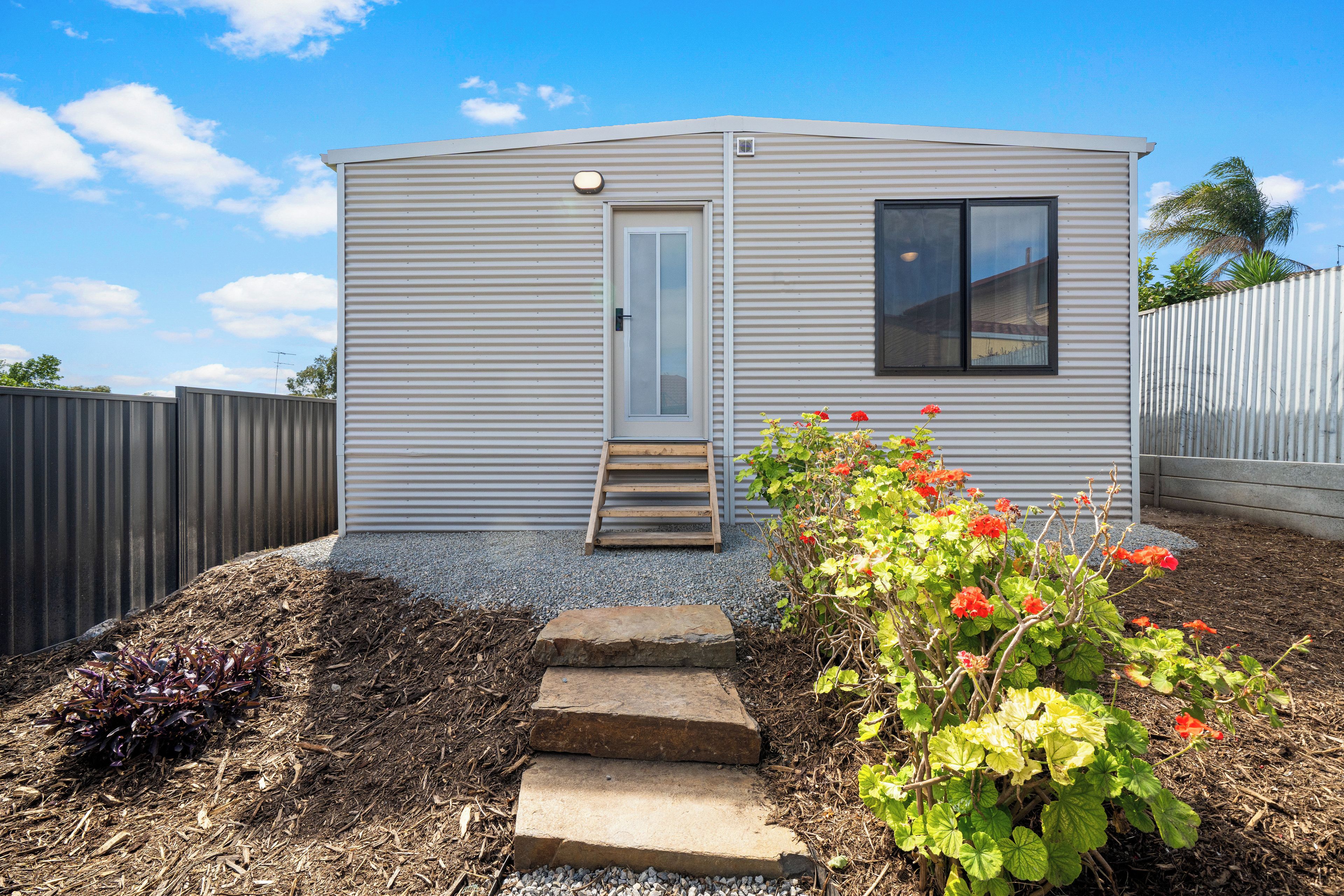 A small, single-story mobile home with a front door, a window, and a small porch area.