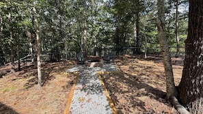 A forested area with a fire pit and two chairs. - Where Peace Meets the Pines (Cleveland)