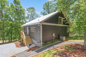A cabin with a wooden exterior, a covered porch, and a small staircase leading to the entrance. - Where Peace Meets the Pines (Cleveland)